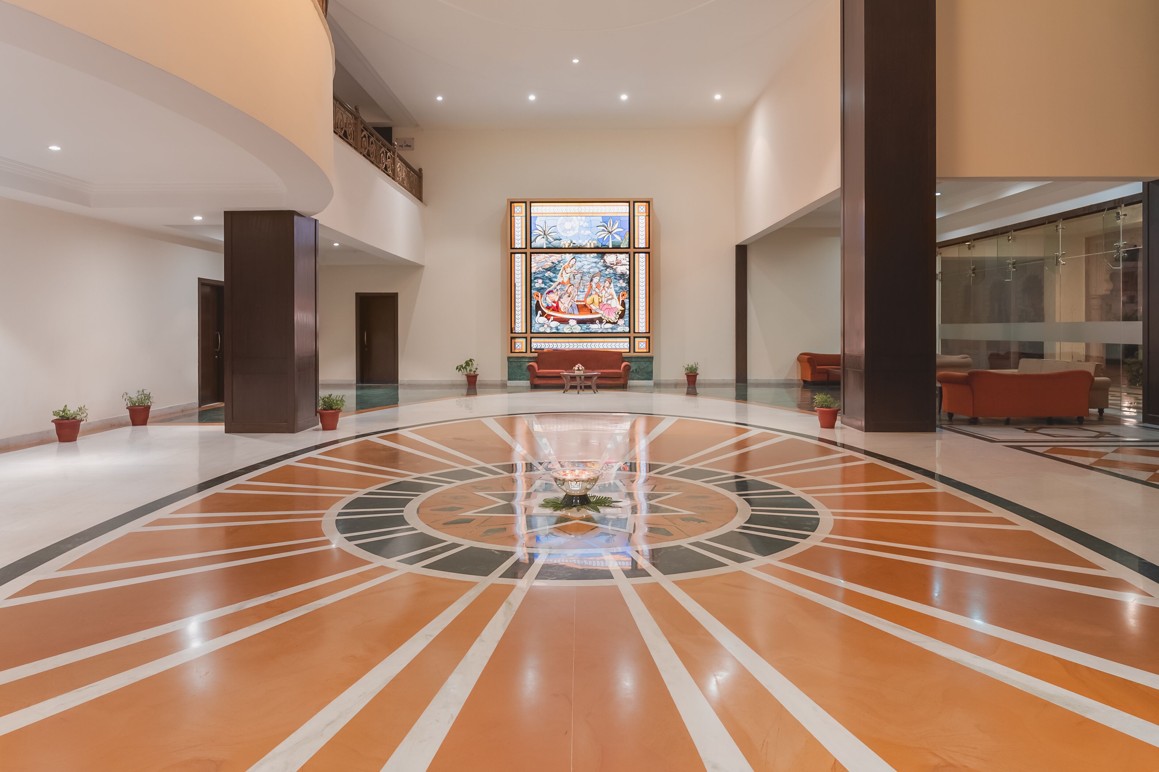 A spacious lobby with a central decorative fountain, a large mural on the back wall, and a modern floor design.