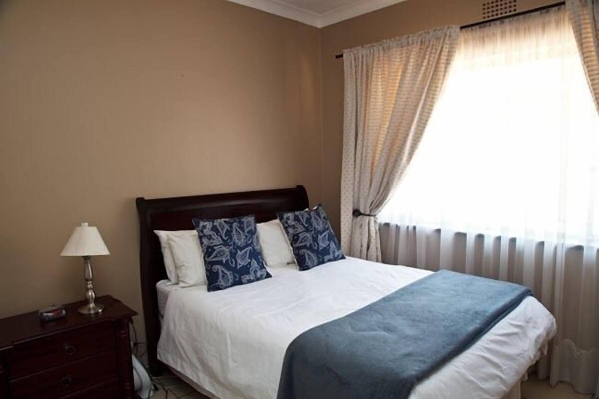 A bedroom with a bed, a nightstand, and a lamp.