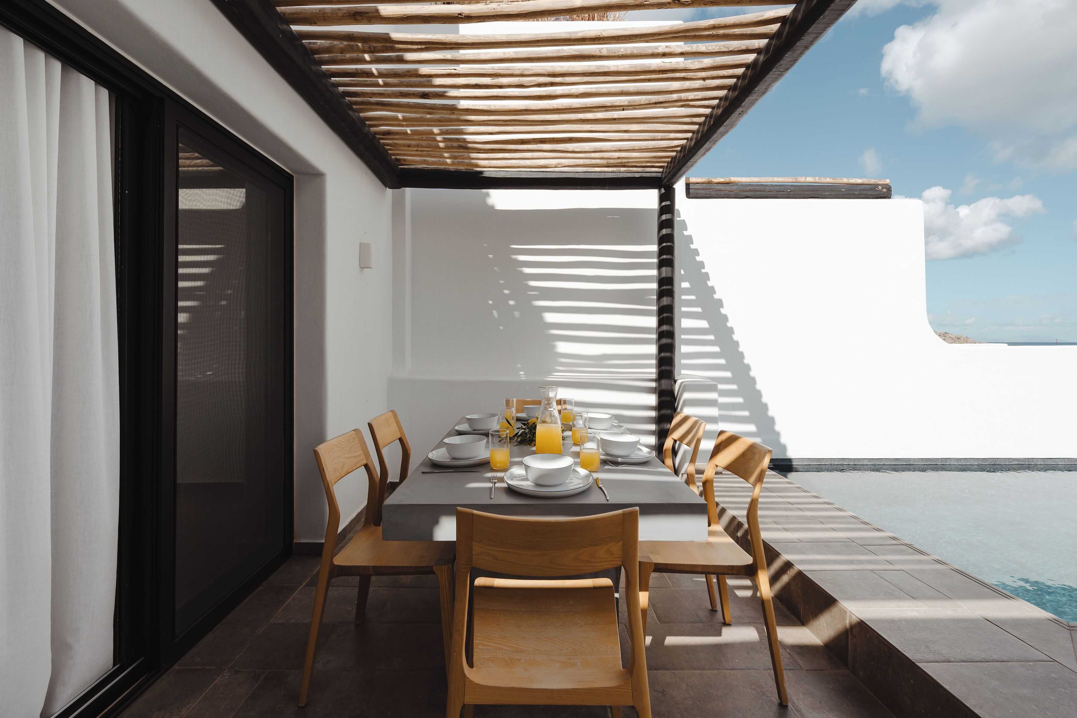 Un coin repas avec une table dressée pour quatre personnes, donnant sur une piscine.