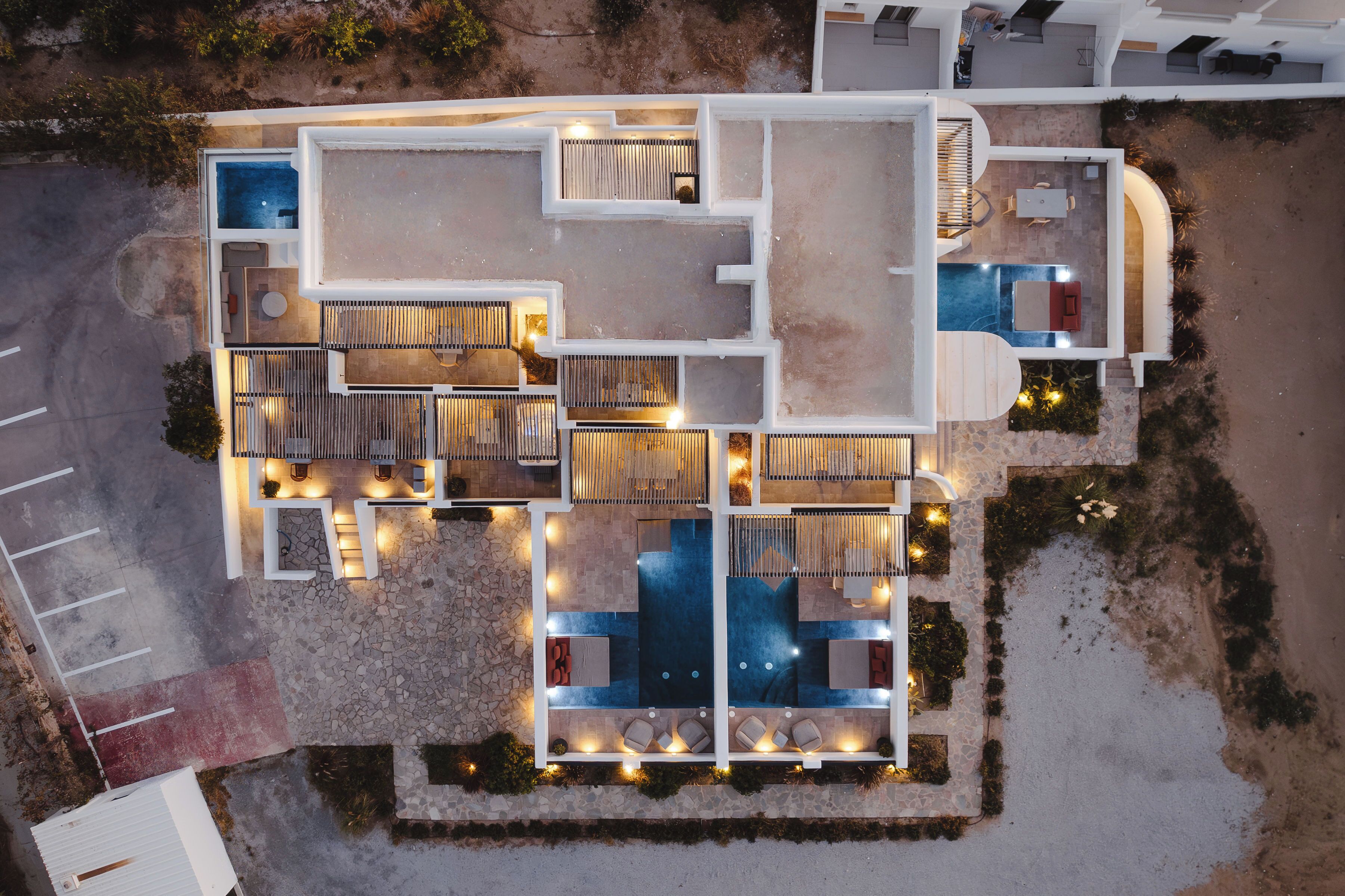 An aerial view of a hotel with multiple rooms, a swimming pool, and outdoor seating areas.