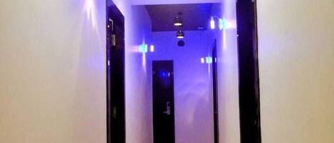 Un pasillo con paredes blancas y un piso brillante, que conduce a una puerta al final.