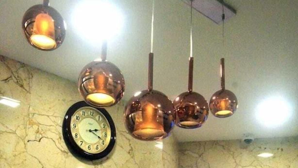 Vestíbulo con pared de mármol, un reloj y lámparas colgantes.