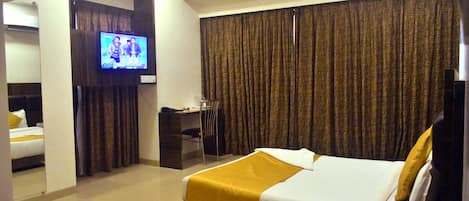 A hotel room with a bed, a desk, a chair, a television, and curtains.