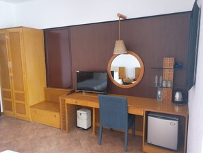 Compact room with a functional layout, featuring a desk area with TV, refrigerator, and chair.