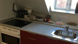 Una cocina compacta con un lavamanos doble, una estufa y una ventana sobre el lavamanos.