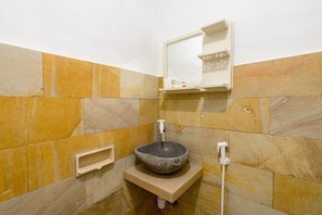 A bathroom with a stone sink, a mirror, and a towel rack.