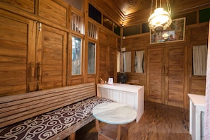 A wooden interior with a bench, a small round table, and a hanging light fixture.