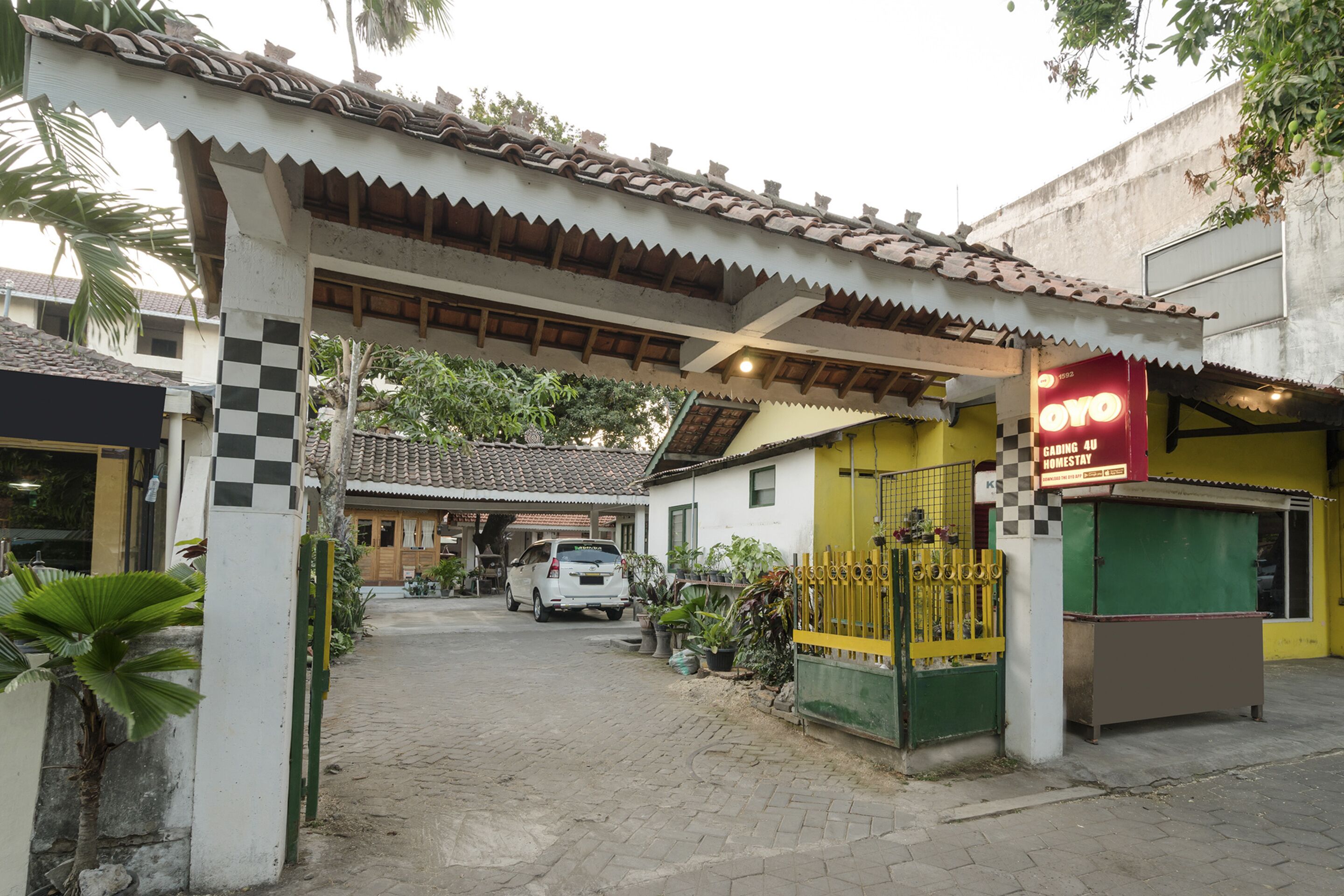 Un edificio tradicional con techo de tejas, entrada a cuadros y un letrero que dice 'OYO Homestay'.