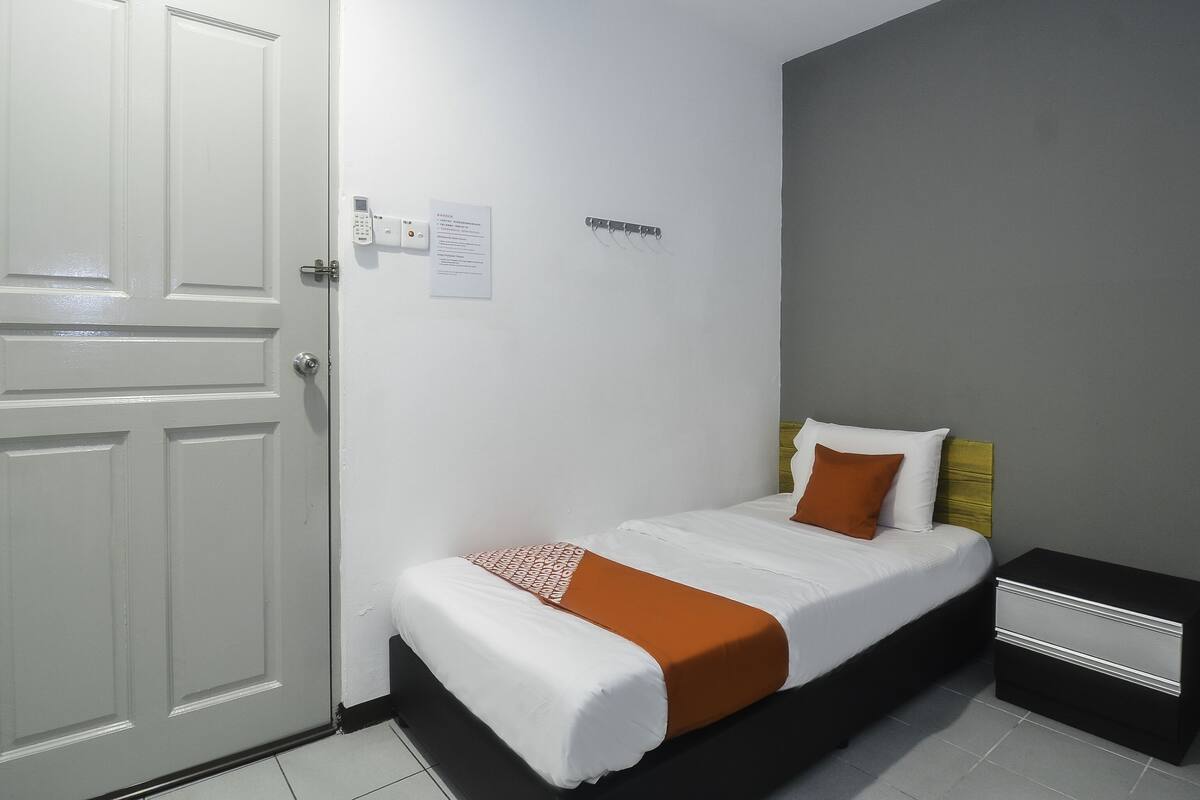 A bedroom with a bed, a bedside table, a heater, and a door.