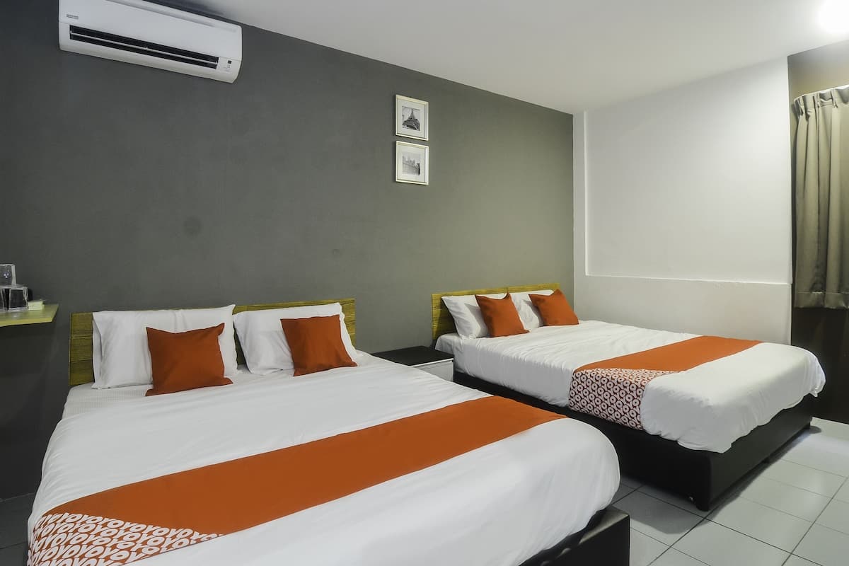 Two beds with white and orange bedding, a grey wall, a framed picture, and an air conditioning unit.