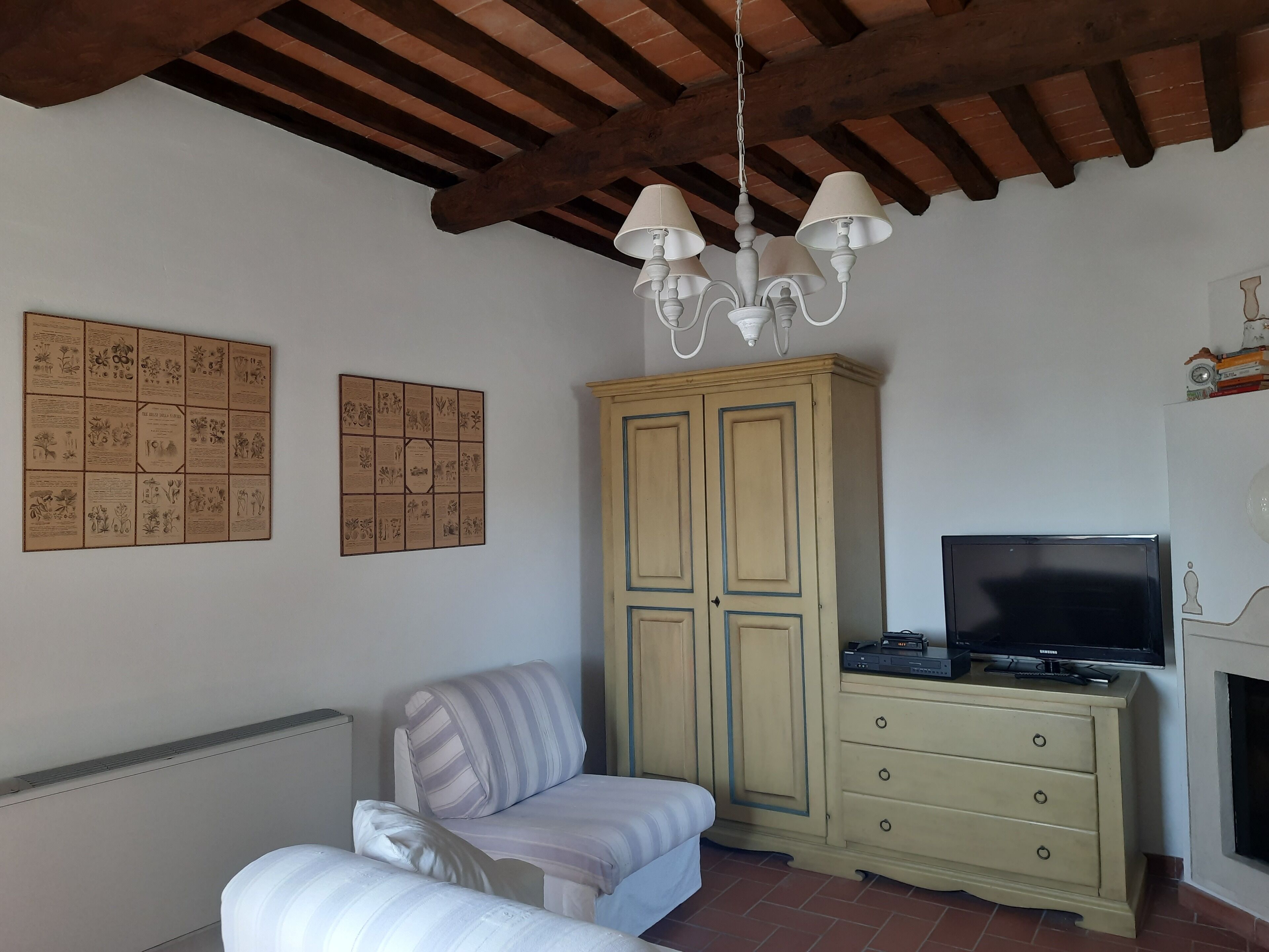 Een woonkamer met een bank, een kast, een televisie en een kroonluchter.
