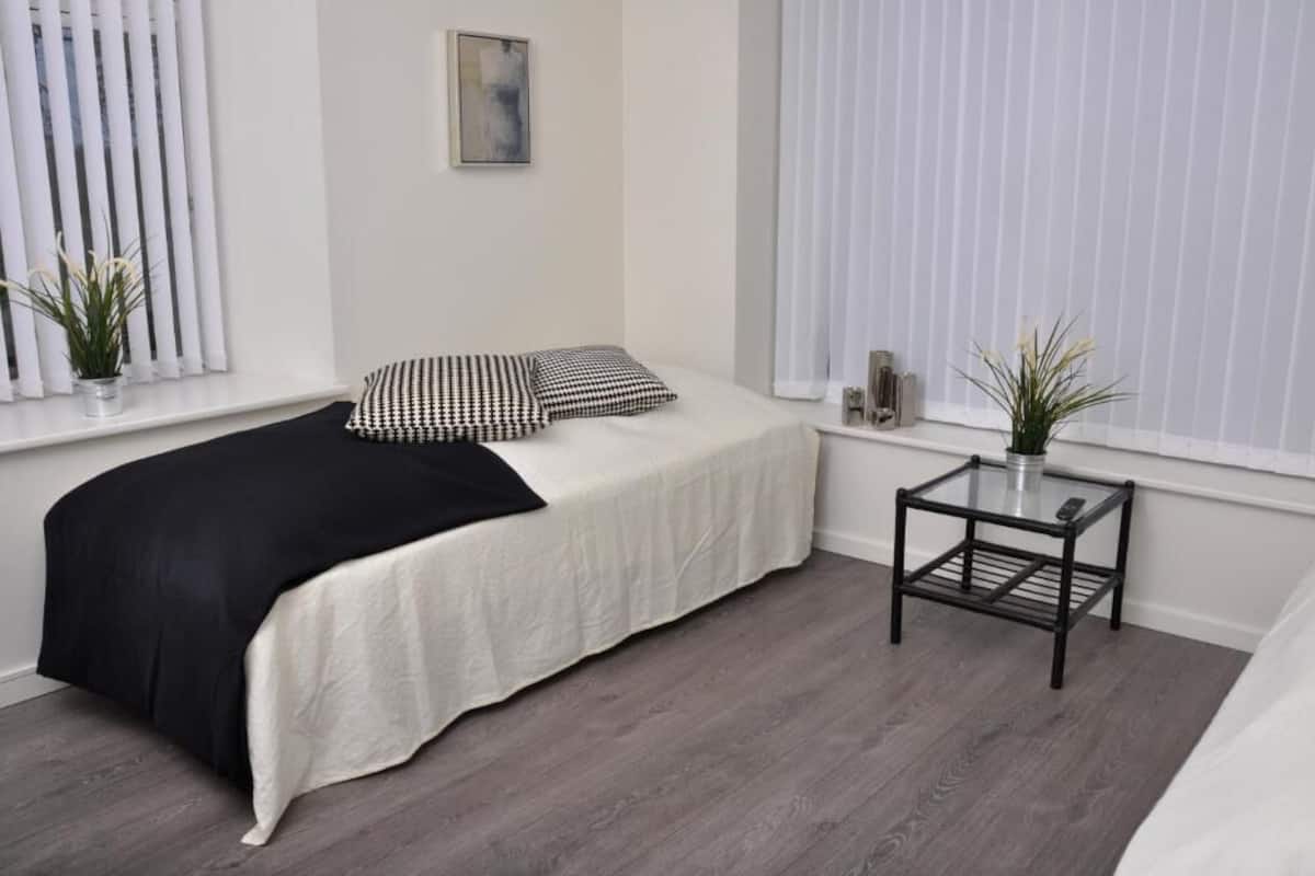 A bedroom with a bed, a small table, and a window with blinds.