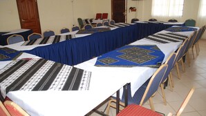 A conference room with long tables covered in patterned tablecloths, arranged in rows with chairs. - The REE (Thika)