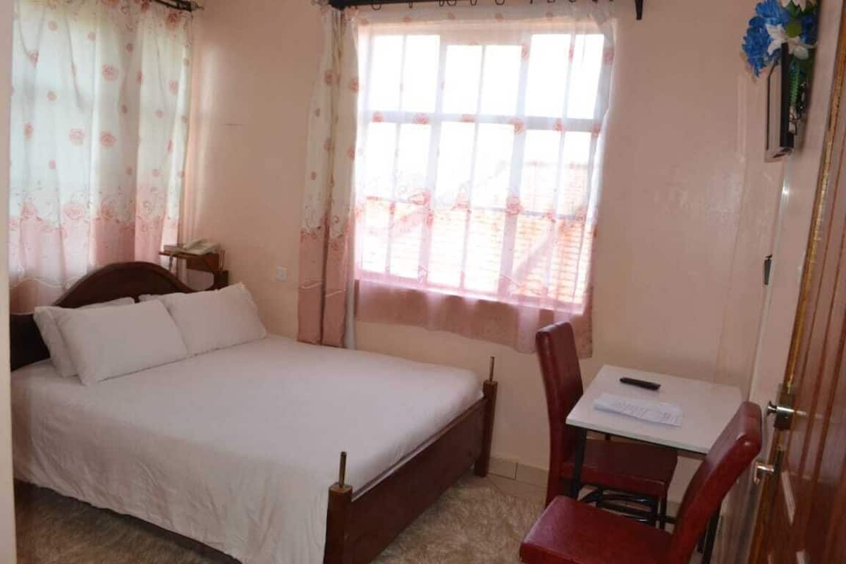 Un dormitorio con cama, escritorio y silla.