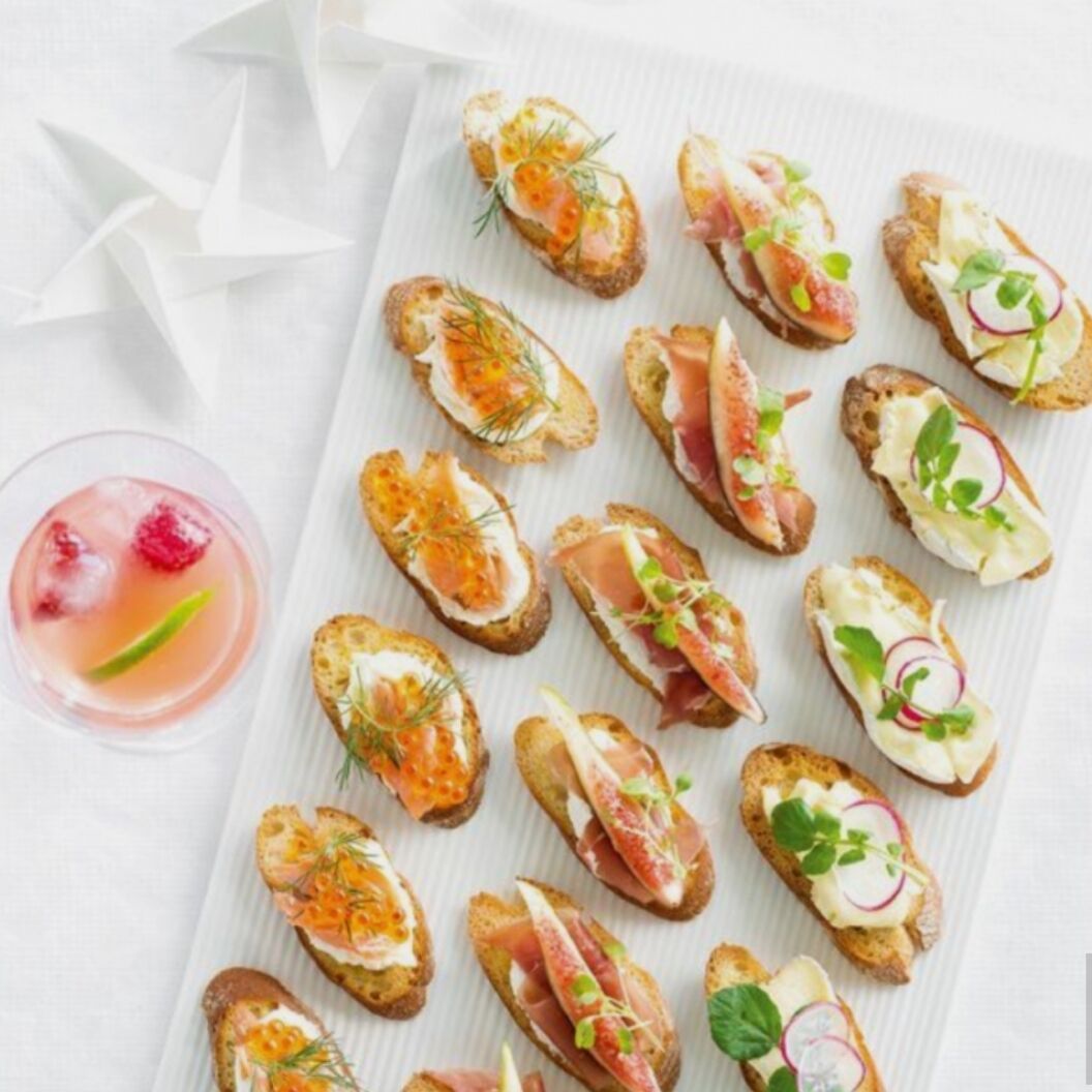A variety of appetizers on a white plate, including items with smoked salmon, cream cheese, and herbs.
