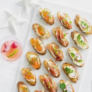A variety of appetizers on a white plate, including items with smoked salmon, cream cheese, and herbs.