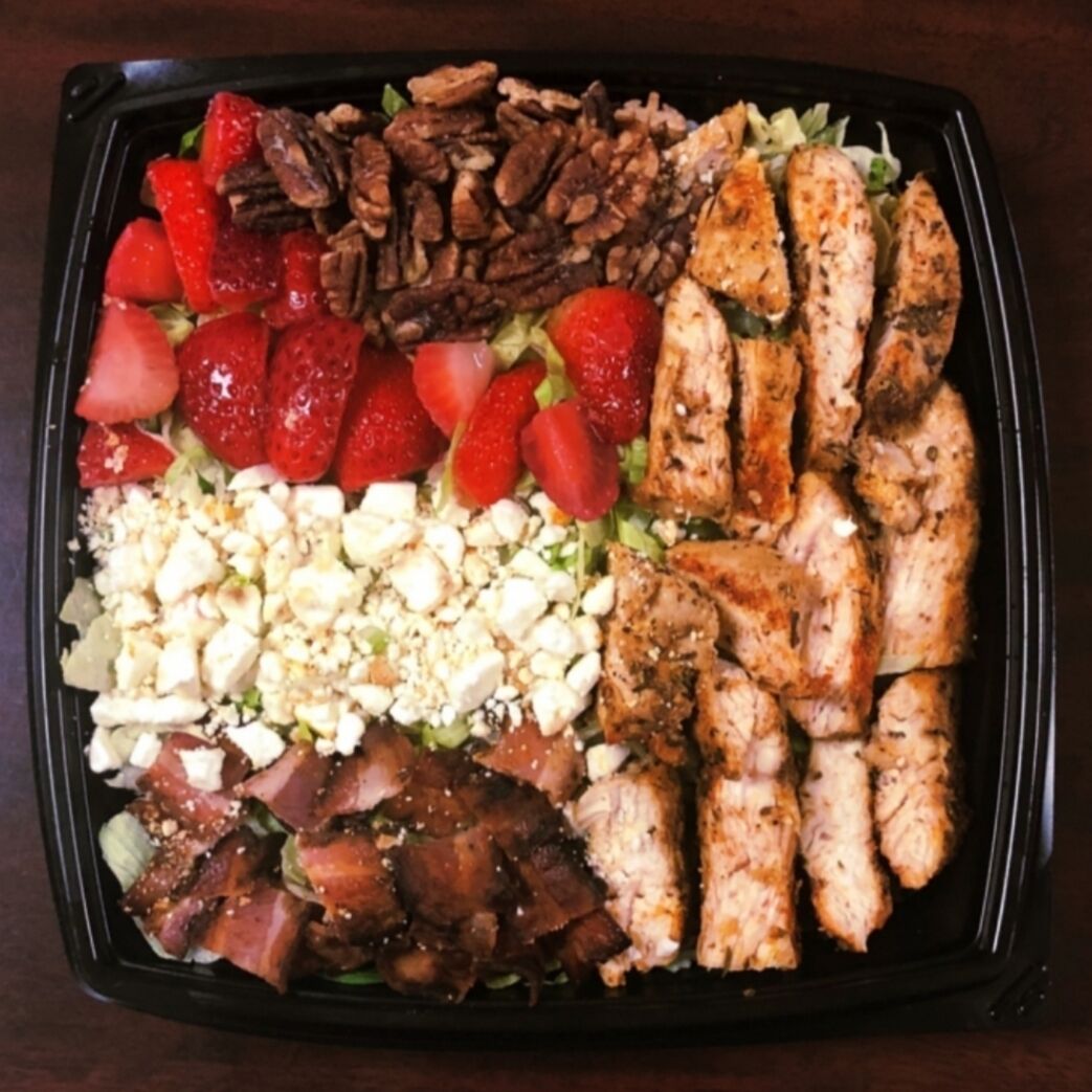 A meal with grilled chicken, strawberries, pecans, and feta cheese.