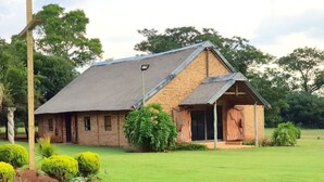 A rustic brick building with a sloped roof and a small attached structure. - Avela (Magaliesberg)