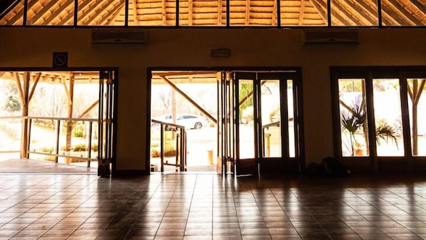 A spacious interior with a high, sloped wooden roof and large windows allowing natural light. - Avela (Magaliesberg)