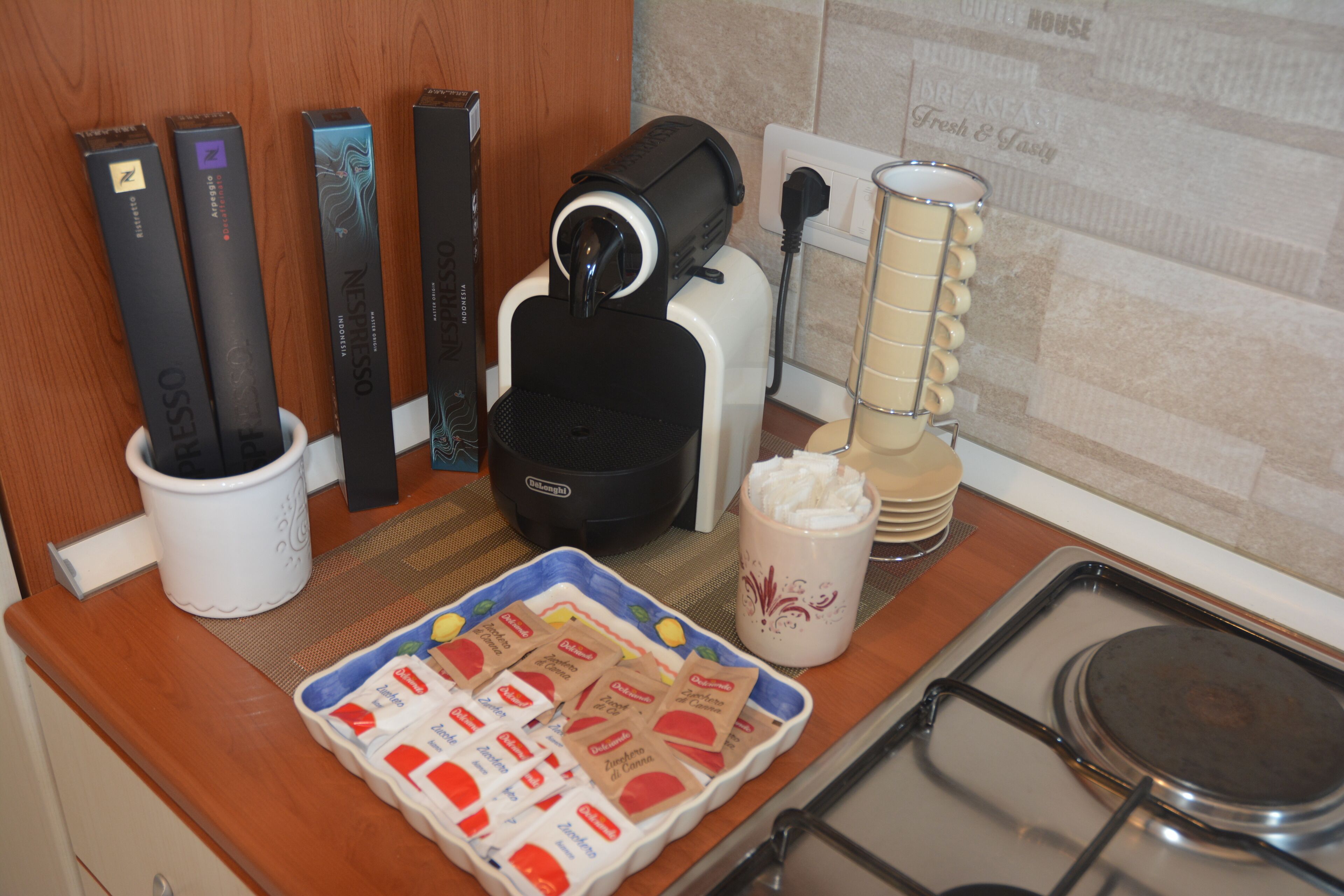 Een aanrecht met een koffiezetapparaat, theezakjes, een mok en een schaal koekjes.