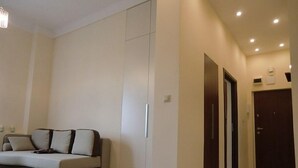 A modern living room with a sofa, a rug, and a hallway leading to an elevator. - Modern Apartment (Warsaw)