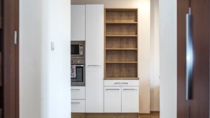 A kitchen with white cabinets, a wooden shelf, and a microwave. - Modern Apartment (Warsaw)