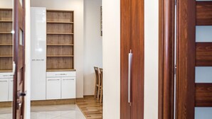 A kitchen with white cabinets, wooden shelves, and a tiled floor. - Modern Apartment (Warsaw)