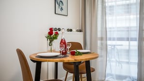 A dining table set with plates, cutlery, a bottle, and a vase with flowers. - Silver Apartments - ul. Klopot (Warsaw)