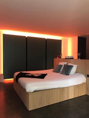 Un dormitorio moderno con cama, mesitas de noche y televisor montado en la pared.