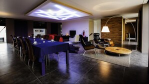 Une salle de conférence moderne équipée d’une longue table, de chaises, d’une petite table ronde et d’une lampe.