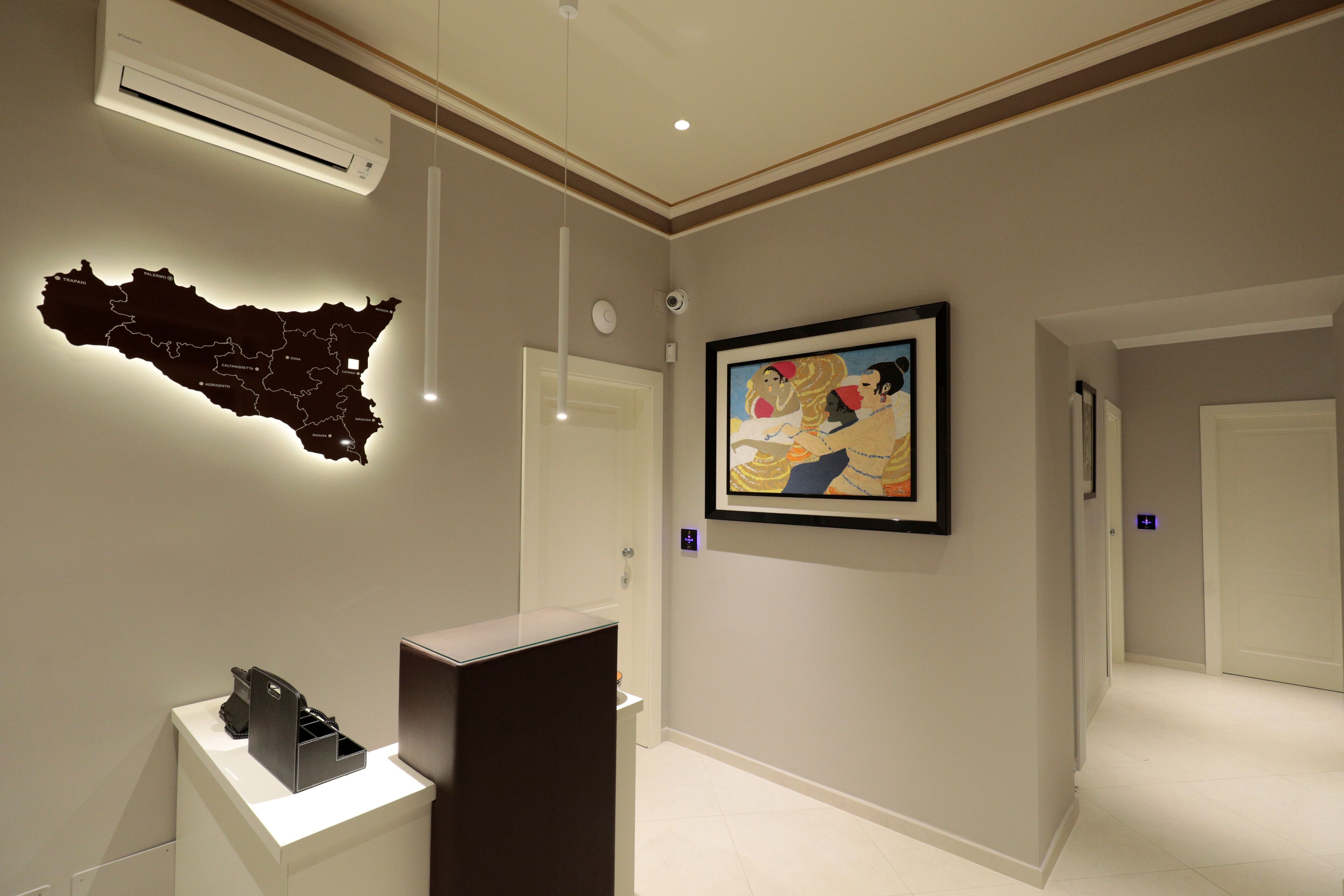 A hallway with a map, a framed painting, and a reception desk.