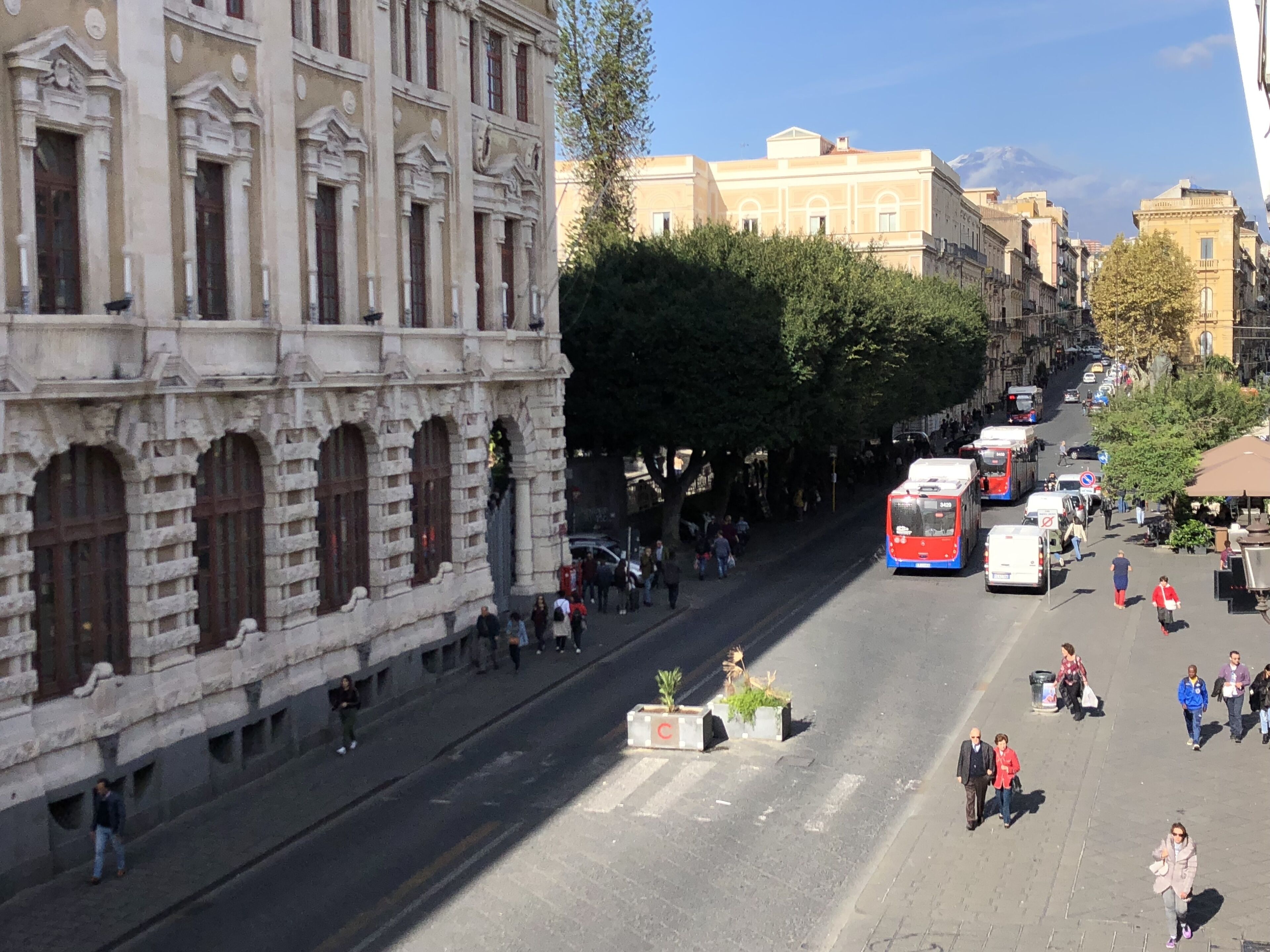 A street with historic buildings, a tram, and pedestrians.