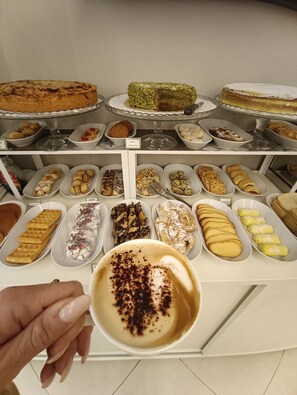 A dessert display with various pastries and a cup of coffee.