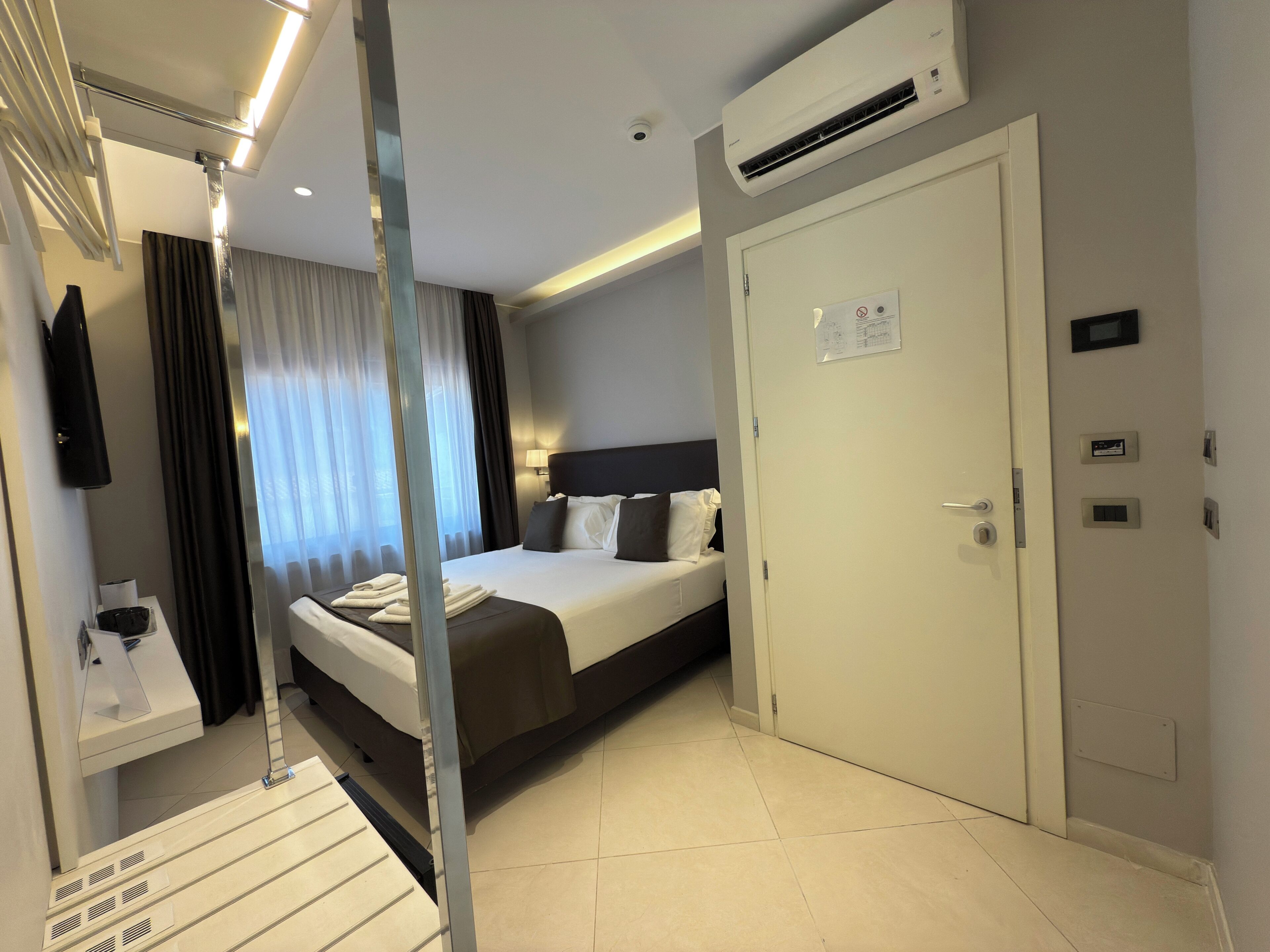 Habitación de hotel con cama, armario, equipo de aire acondicionado y una puerta con cerradura.