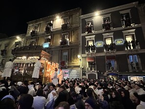 A crowded street scene with people gathered around a brightly lit building with ornate decorations.
