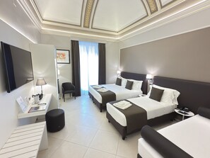 A hotel room with two beds, a desk, a chair, a TV, and a window with curtains.