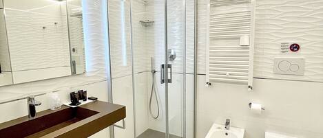 A modern bathroom with a glass-enclosed shower, a vanity with a sink, a bidet, and a toilet.