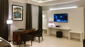 Una habitación de hotel con comedor, televisión y un cuadro en la pared.