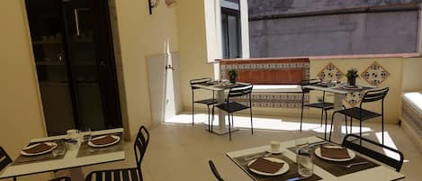 Un comedor con mesas y sillas, un refrigerador y vistas al exterior.