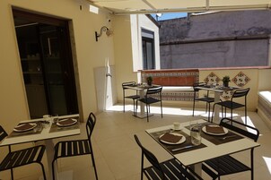 Zona pranzo con tavoli e sedie, un frigorifero e vista sull'esterno.