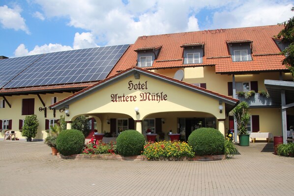 A hotel with a yellow facade, solar panels on the roof, and a sign reading "Hotel Alte Mühle". - Untere Mühle 1 (Langerringen)