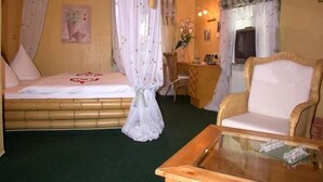 Een kamer met een bed, een stoel, een bureau en een glazen tafel.