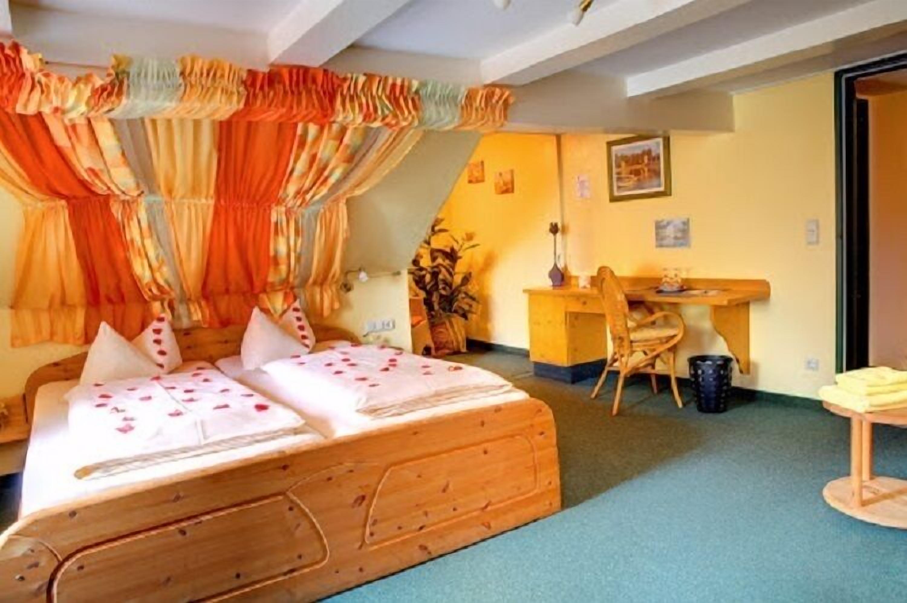 A room with a wooden bed, a desk, and a chair.