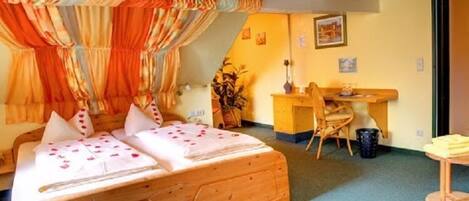 A room with a wooden bed, a desk, and a chair.