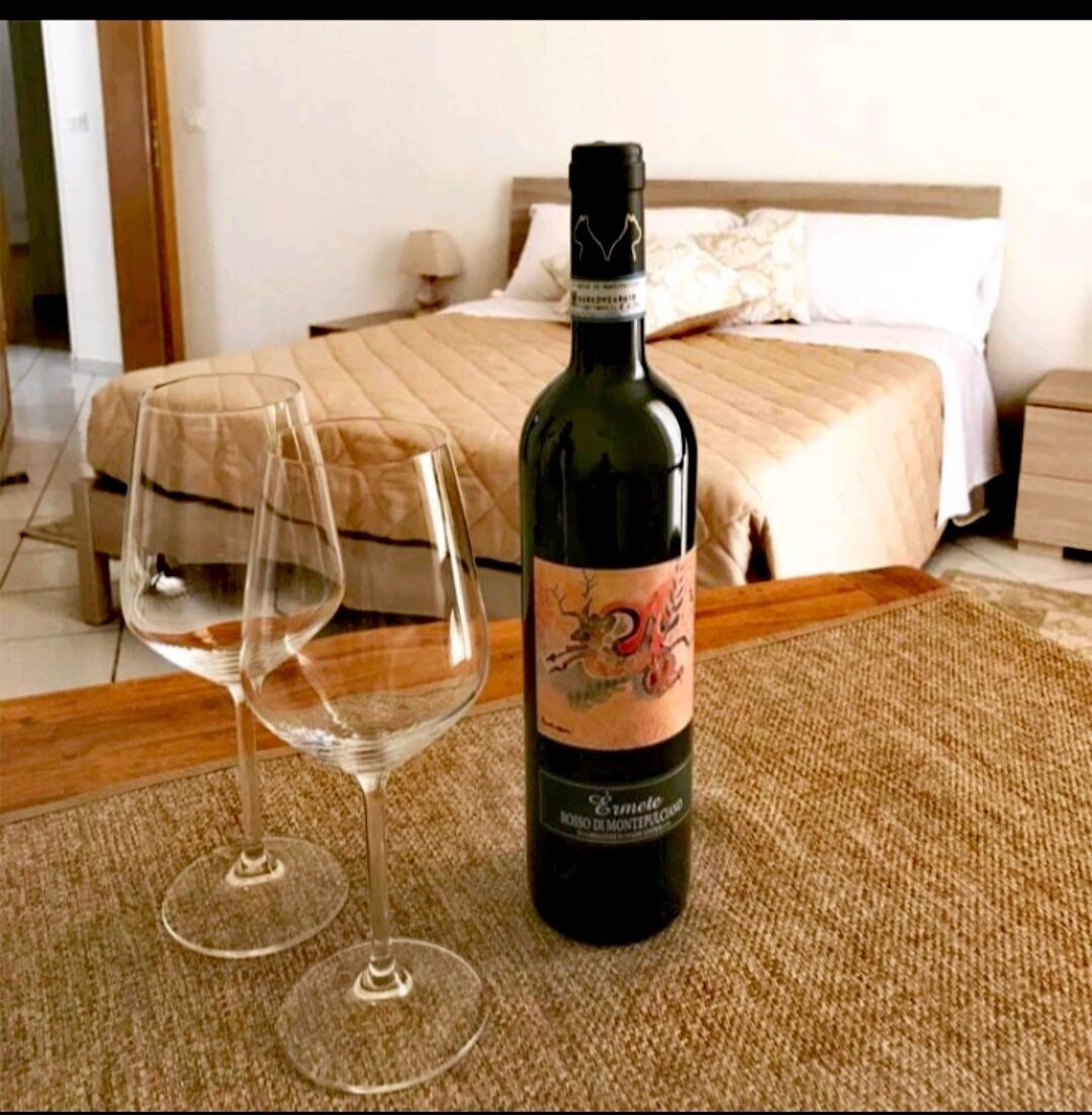 Een fles wijn en twee lege wijnkannen op een houten tafel in een hotelkamer.