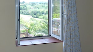 Een kamer met een groot raam dat uitzicht geeft op een groen landschap.
