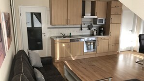 A compact kitchen with wooden cabinets, a built-in microwave, and a stainless steel oven. - Cozy and bright furnished apartment centrally located (Norderney)