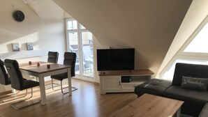 A modern living space with a dining area, a TV, and a sofa. - Cozy and bright furnished apartment centrally located (Norderney)