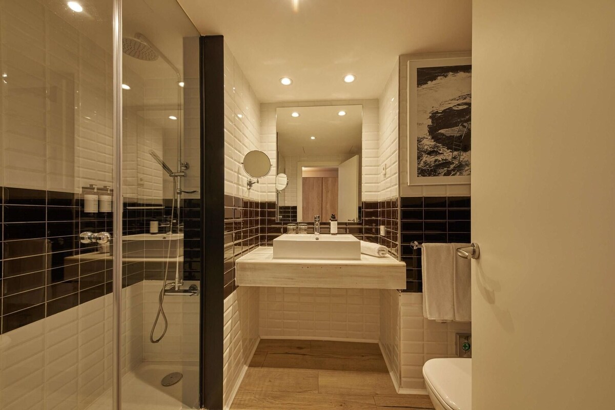 A modern bathroom with a glass-enclosed shower, a large sink, and a toilet.