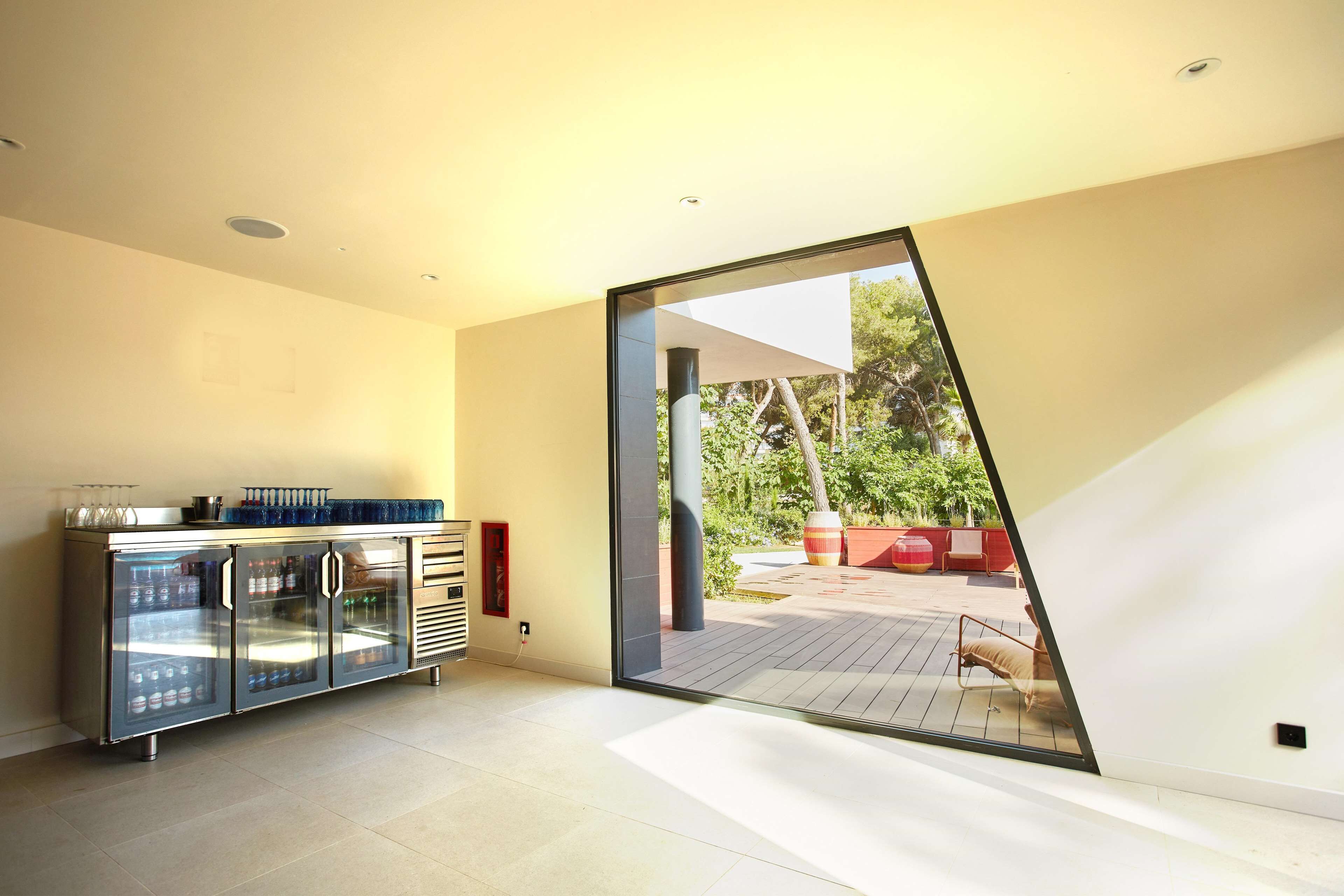 Un interior moderno con cocina de frentes de vidrio, puerta corrediza que da a un patio exterior y un diseño minimalista.